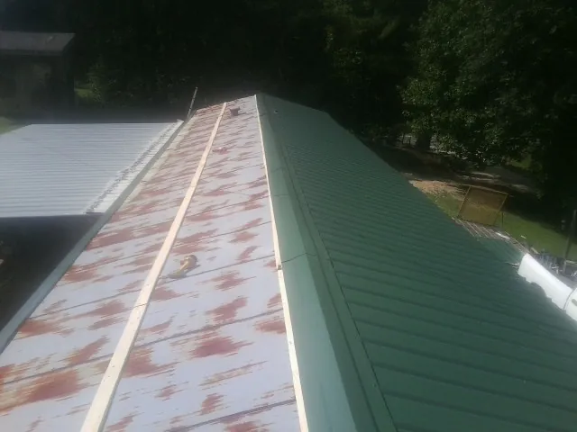 Old rusted panels beside newly installed green metal roofing — Wind Damage Roof Repair by Roofing Brothers in Durango